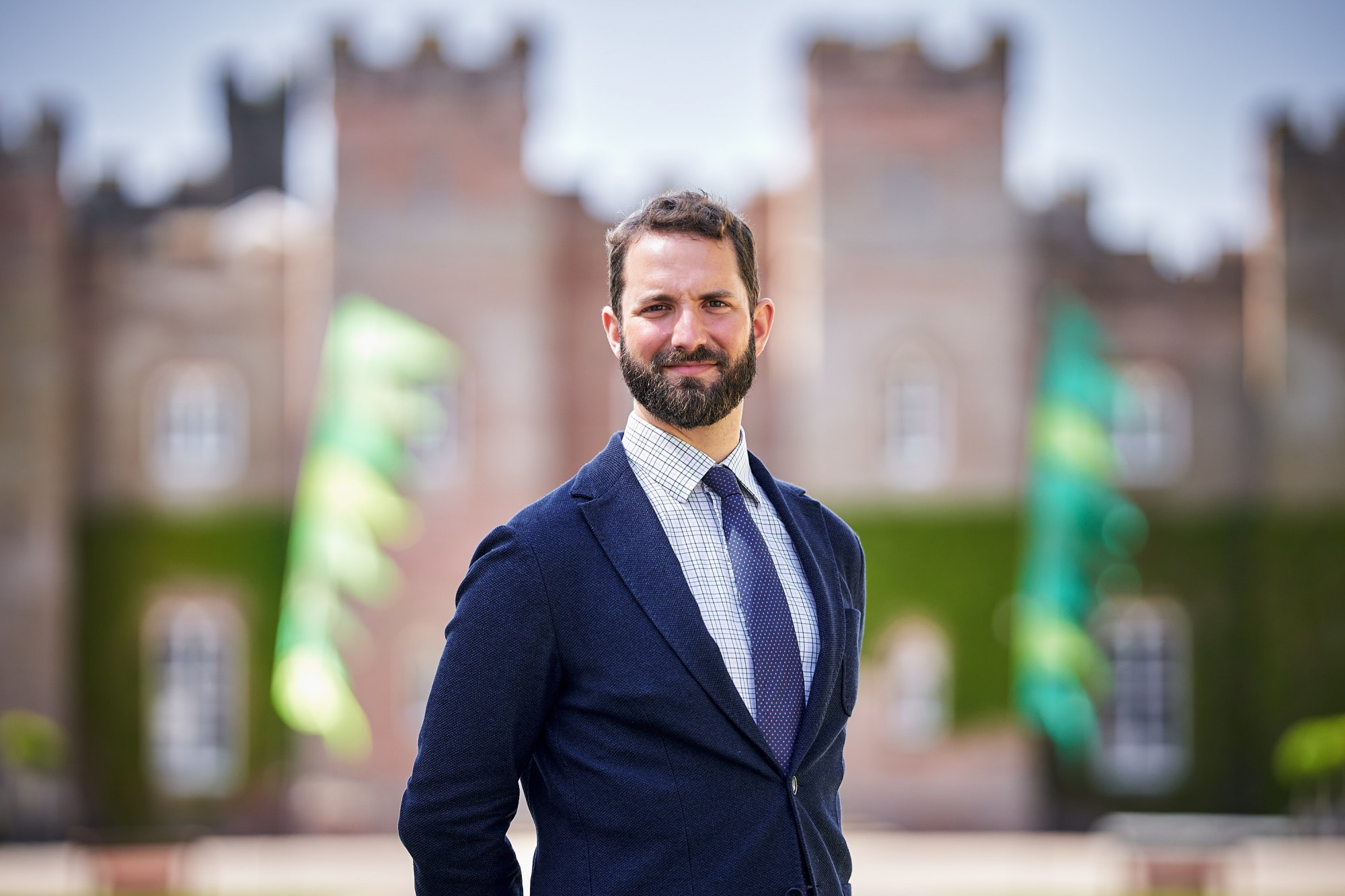 head and shoulder photo of William Stormont wearing a navy suit jacket and tie, with the front of scone palace blurred in the background.